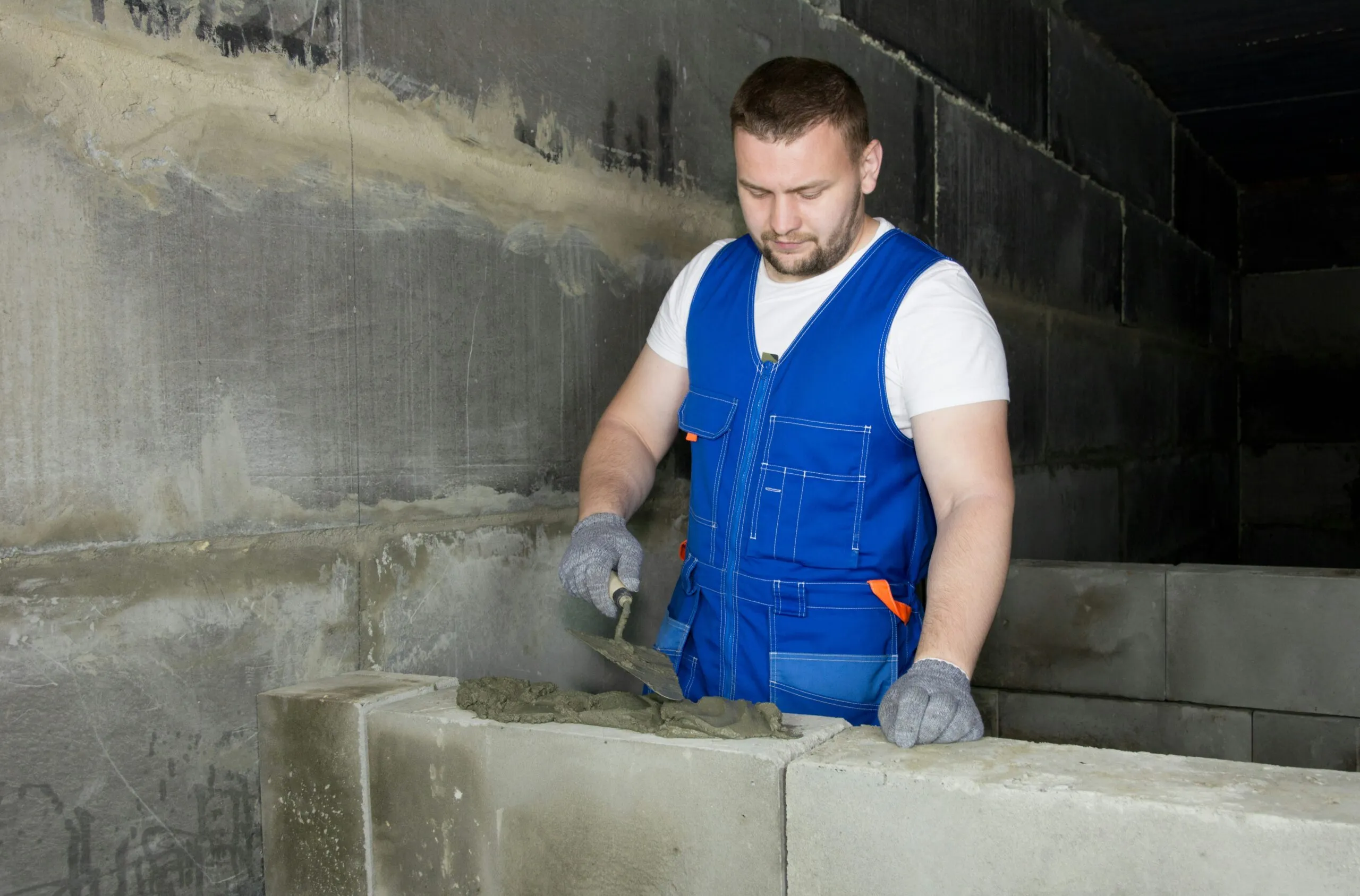 Design Patterns in Java: Builder Design Pattern. A man laying bricks for building construction.